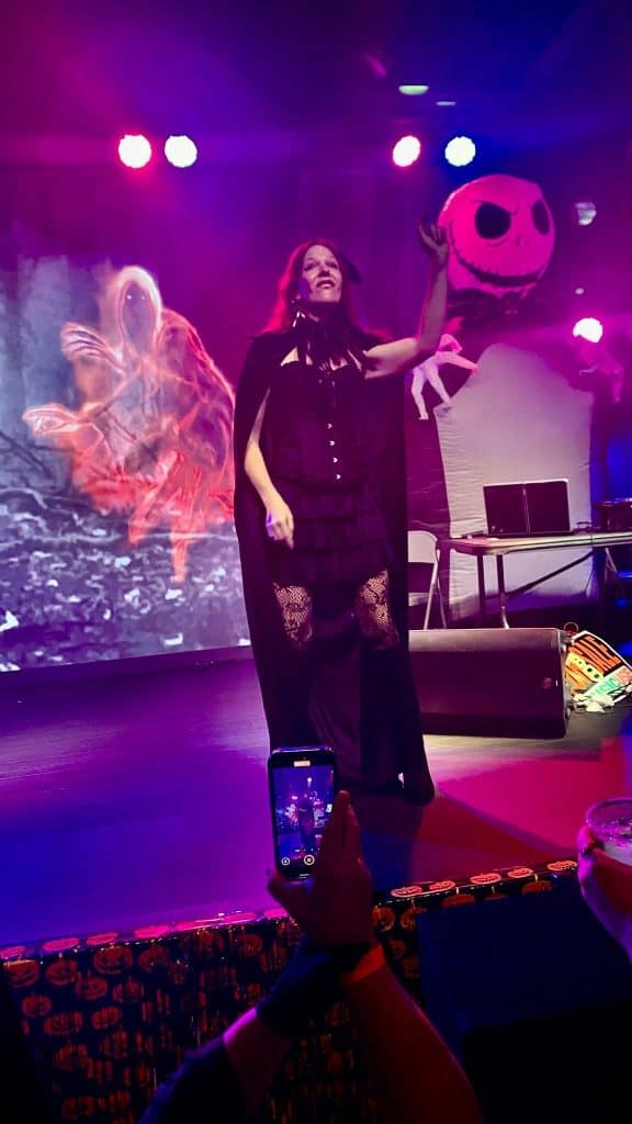 Rach performing in ASL on stage under pink and purple lights