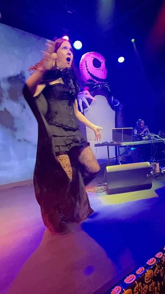 Rach signing a performance on stage under purple lights